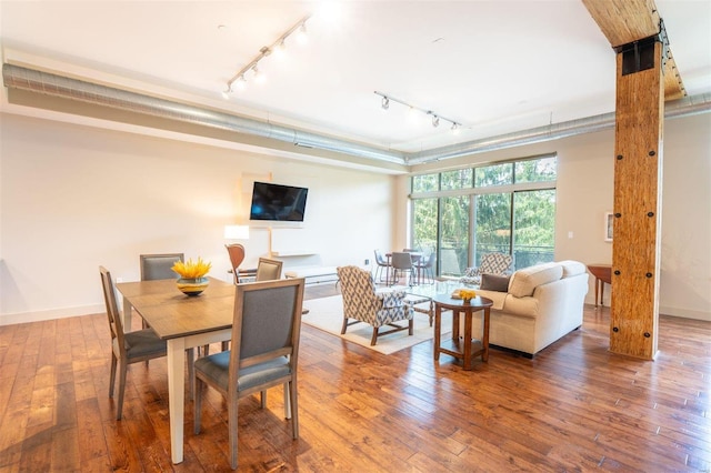 dining area with wood-type flooring and track lighting