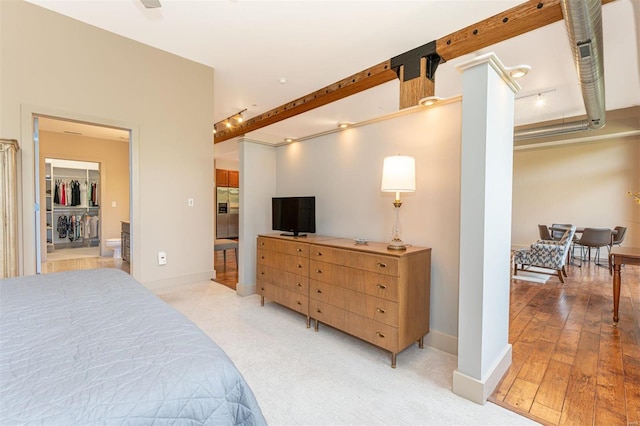 bedroom featuring light hardwood / wood-style flooring, a closet, stainless steel refrigerator with ice dispenser, and a walk in closet