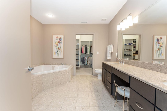 bathroom with toilet, tile patterned floors, double vanity, and a relaxing tiled tub