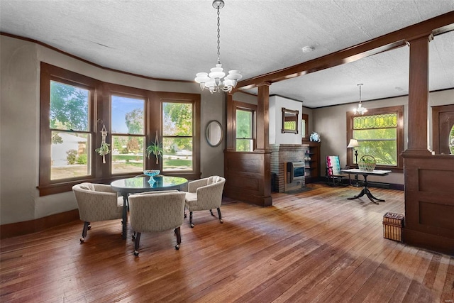 dining space featuring a fireplace, a chandelier, a textured ceiling, and hardwood / wood-style flooring