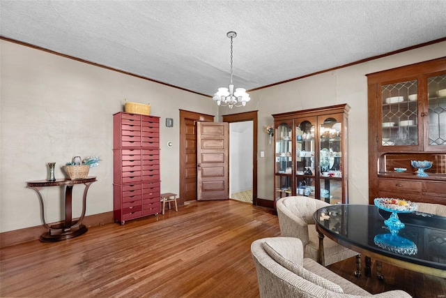 dining area featuring crown molding, dark wood-type flooring, a textured ceiling, and a notable chandelier