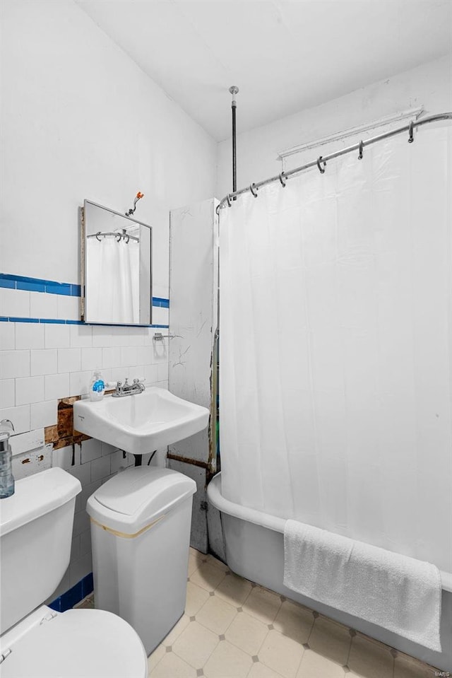 full bathroom featuring sink, shower / tub combo, tile walls, and toilet