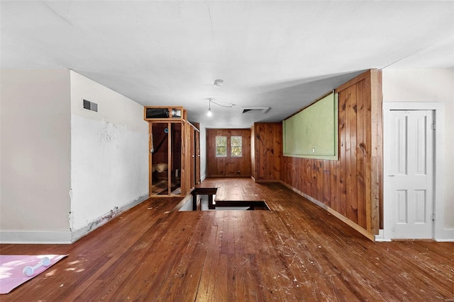 unfurnished living room with wooden walls and wood-type flooring