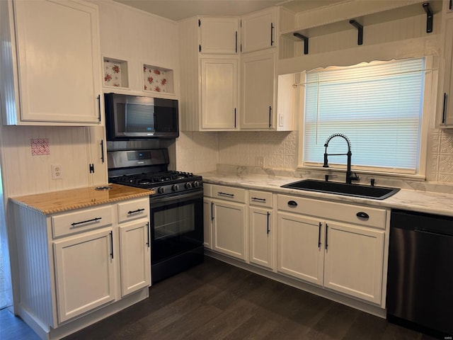 kitchen featuring appliances with stainless steel finishes, light stone countertops, dark hardwood / wood-style flooring, white cabinetry, and sink