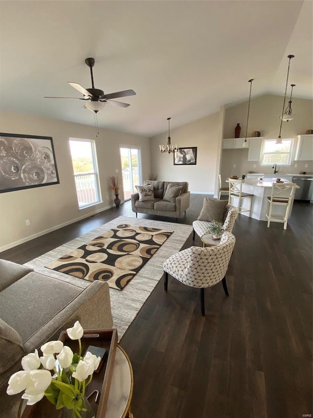 living room with ceiling fan with notable chandelier, dark hardwood / wood-style floors, and lofted ceiling