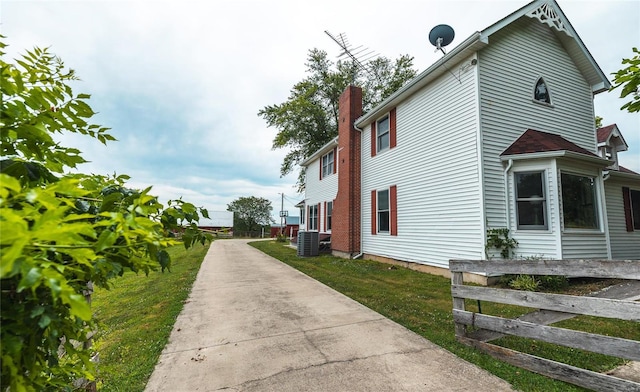 view of side of property featuring central AC unit and a yard