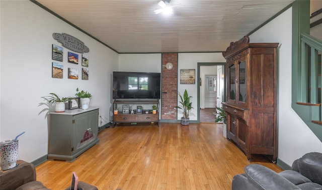 living room with brick wall, crown molding, and light wood-type flooring