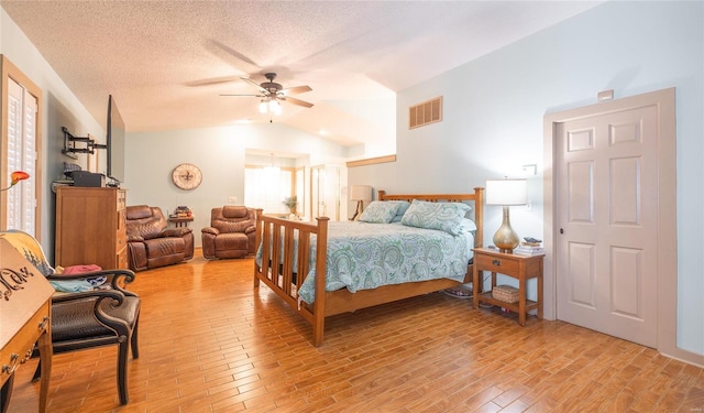 bedroom with light hardwood / wood-style floors, a textured ceiling, ceiling fan, and vaulted ceiling