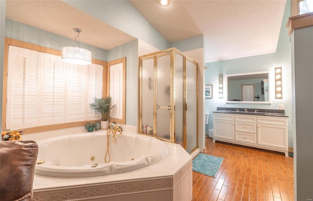 bathroom featuring plus walk in shower, double vanity, a textured ceiling, lofted ceiling, and hardwood / wood-style flooring