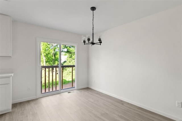 unfurnished dining area featuring light wood-type flooring and an inviting chandelier