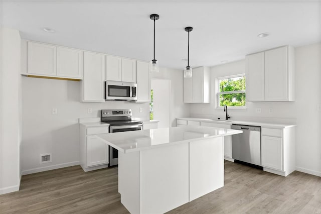 kitchen with white cabinets, a center island, appliances with stainless steel finishes, and pendant lighting