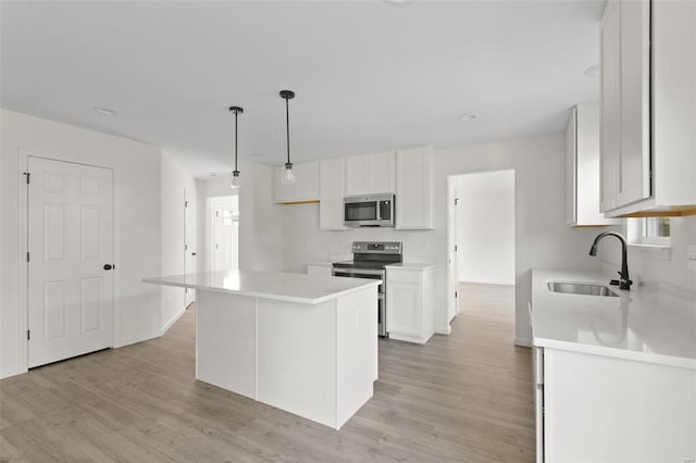 kitchen with pendant lighting, sink, a kitchen island, white cabinetry, and stainless steel appliances