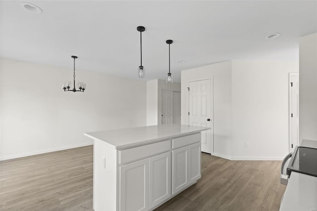 kitchen with white cabinetry, a center island, hanging light fixtures, and light hardwood / wood-style flooring