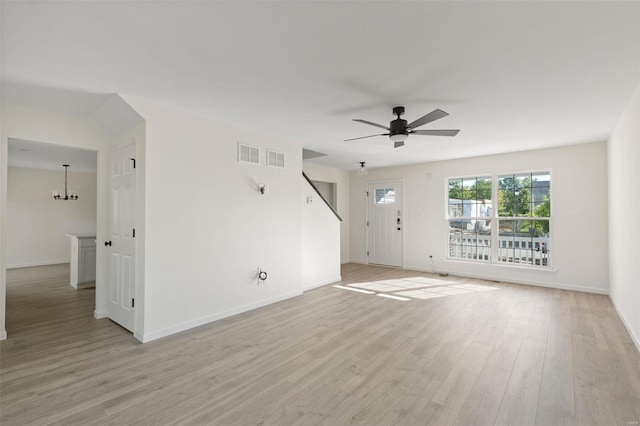 empty room featuring ceiling fan with notable chandelier and light wood-type flooring