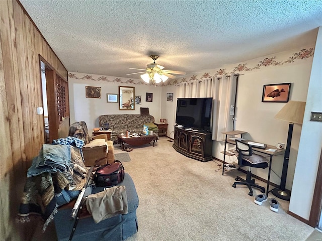 carpeted living room featuring wood walls, a textured ceiling, and ceiling fan