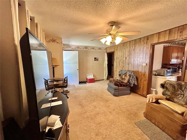 sitting room with wooden walls, a textured ceiling, light colored carpet, and ceiling fan