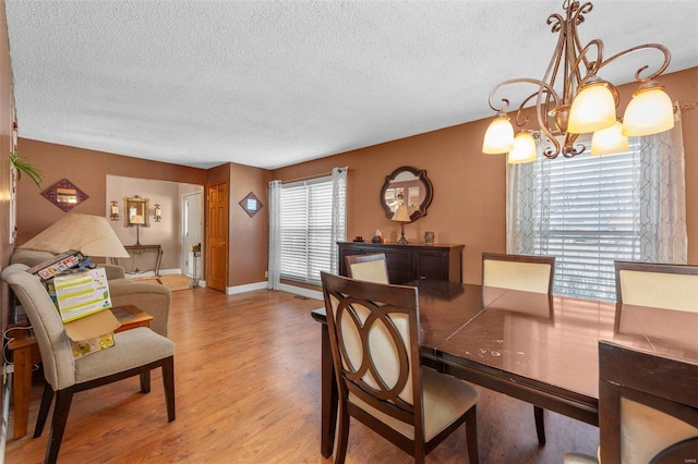 dining space with a notable chandelier, a textured ceiling, and light wood-type flooring