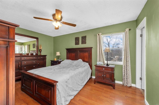 bedroom with a textured ceiling, light hardwood / wood-style flooring, and ceiling fan