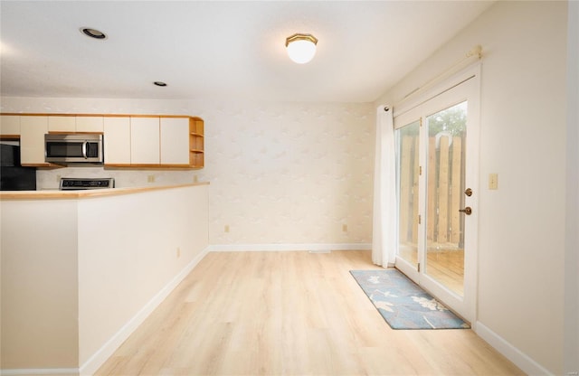 kitchen with light hardwood / wood-style floors, black fridge, and range