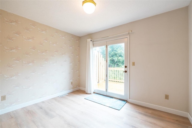 empty room with a textured ceiling and light hardwood / wood-style flooring