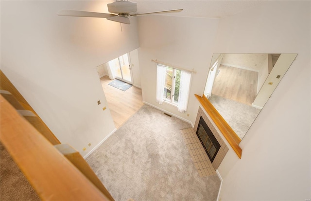 bonus room featuring a towering ceiling, light colored carpet, ceiling fan, and a tiled fireplace