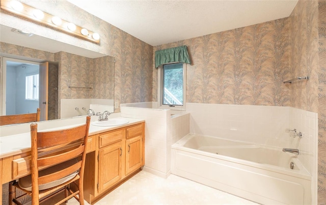 bathroom with a textured ceiling, a bathing tub, and vanity