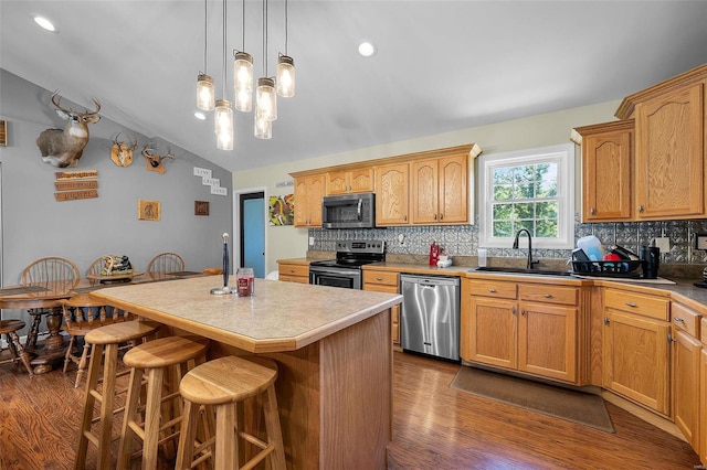 kitchen with sink, appliances with stainless steel finishes, a center island, vaulted ceiling, and dark hardwood / wood-style flooring