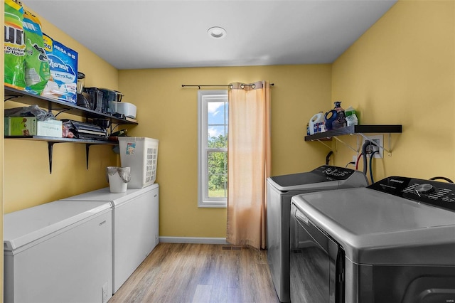 washroom with light hardwood / wood-style floors and washing machine and dryer