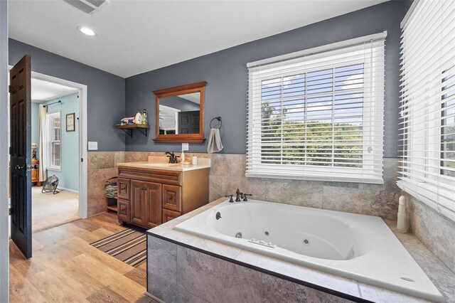 bathroom with vanity, wood-type flooring, and tiled bath