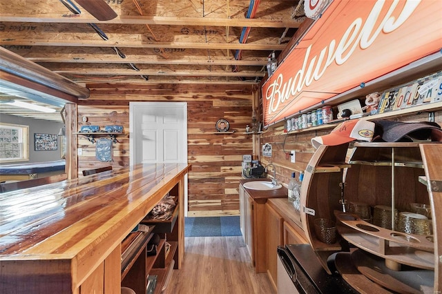 interior space featuring wood-type flooring, wood walls, and sink