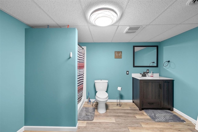 bathroom with vanity, a paneled ceiling, hardwood / wood-style floors, and toilet