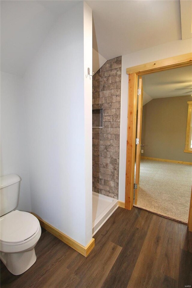 bathroom featuring toilet, wood-type flooring, lofted ceiling, and walk in shower