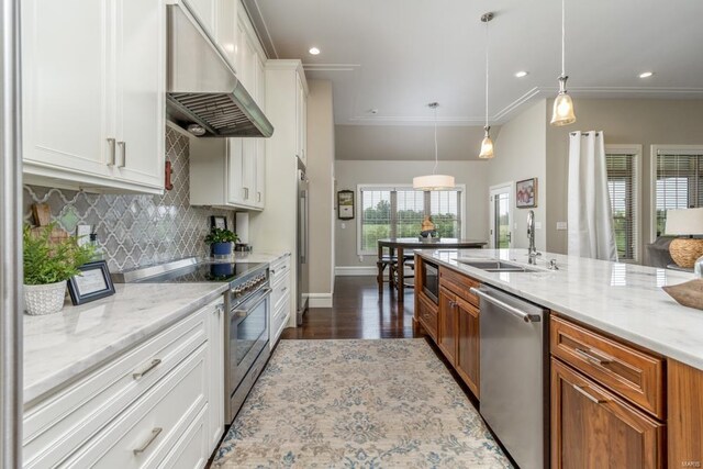 kitchen with dark hardwood / wood-style flooring, stainless steel appliances, wall chimney exhaust hood, pendant lighting, and sink