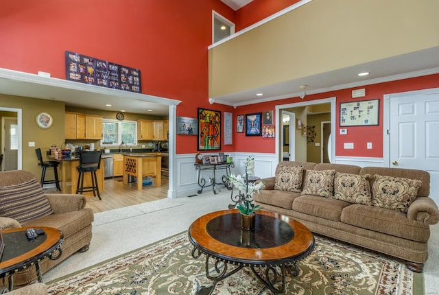 living room featuring ornamental molding, light wood-type flooring, and a towering ceiling