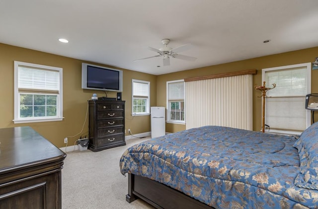 bedroom featuring multiple windows, carpet floors, white refrigerator, and ceiling fan