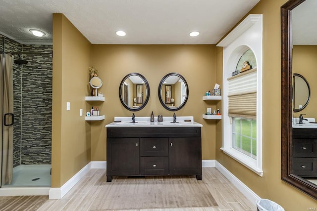 bathroom with tile patterned floors, dual vanity, a shower with door, and a textured ceiling