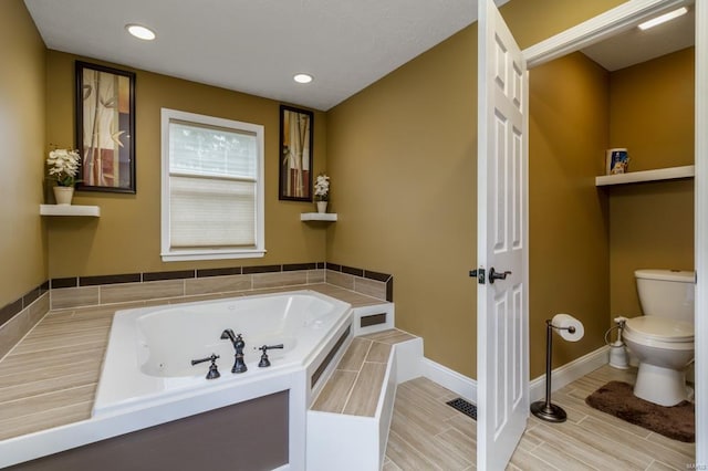 bathroom with tile patterned flooring, a bath, and toilet