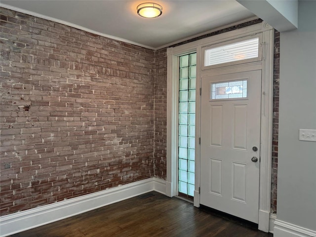 foyer with dark hardwood / wood-style flooring, brick wall, and ornamental molding