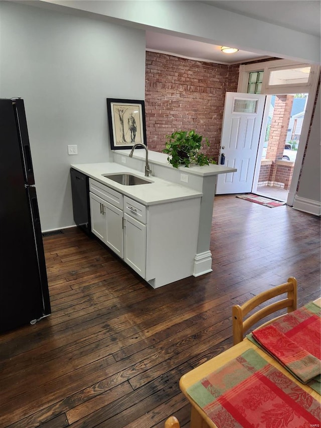 kitchen with white cabinetry, sink, brick wall, kitchen peninsula, and black appliances