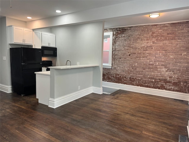 kitchen with white cabinetry, dark hardwood / wood-style flooring, brick wall, kitchen peninsula, and black appliances