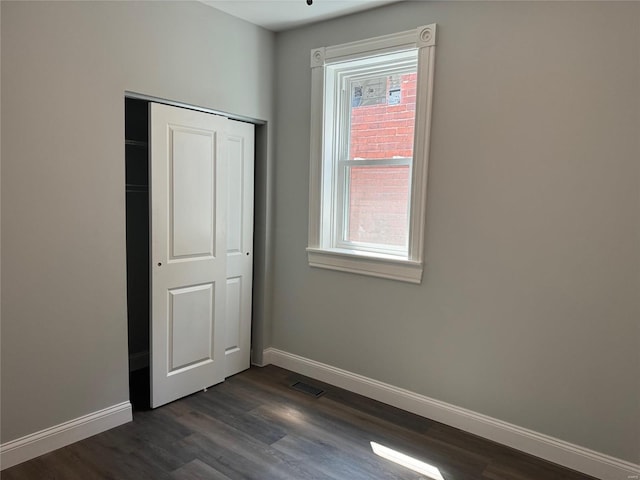 unfurnished bedroom with dark hardwood / wood-style flooring and a closet