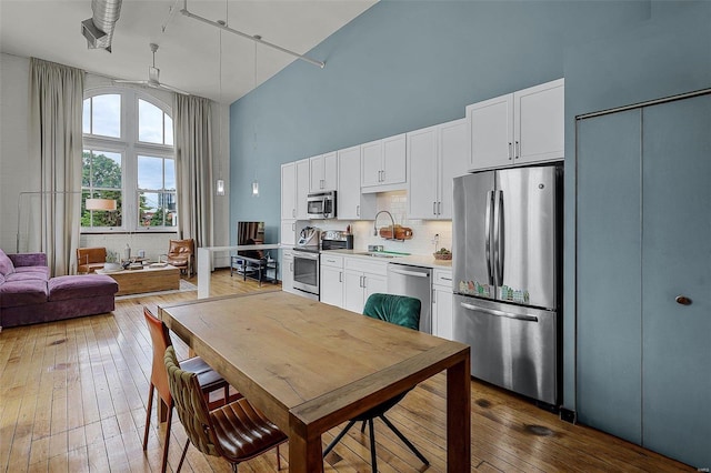 kitchen with dark wood-type flooring, sink, a towering ceiling, stainless steel appliances, and white cabinets