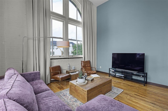 living room featuring brick wall and light wood-type flooring