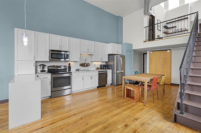 kitchen featuring hanging light fixtures, a high ceiling, and appliances with stainless steel finishes