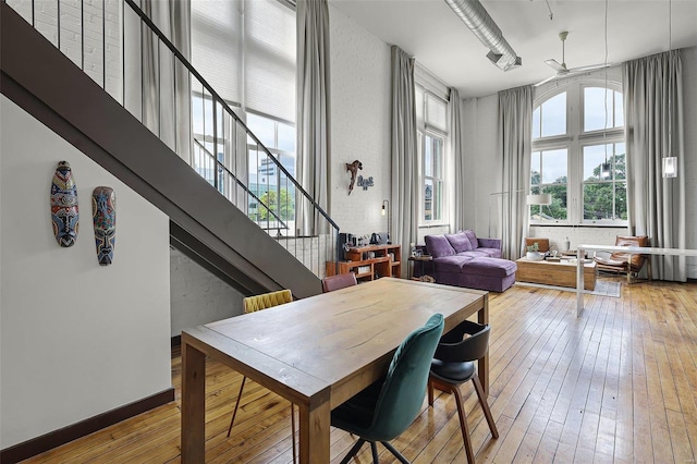 dining space with ceiling fan, a high ceiling, and light wood-type flooring