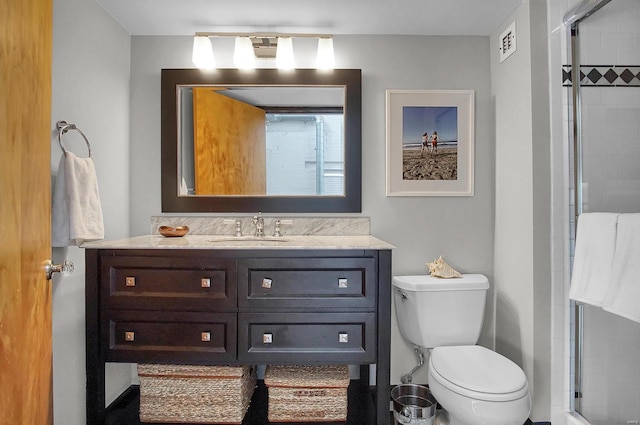 bathroom featuring vanity, toilet, and a shower with shower door