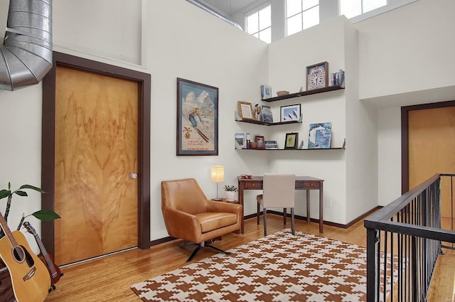 living area with a towering ceiling and light hardwood / wood-style floors