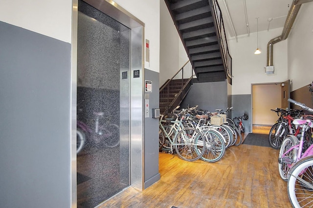 stairs featuring a high ceiling, wood-type flooring, and elevator