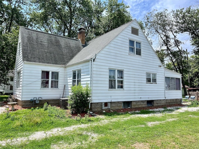 rear view of house featuring central air condition unit and a yard