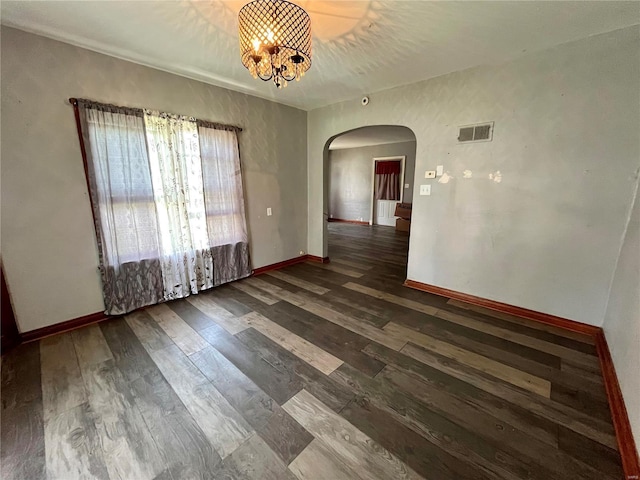 spare room with dark wood-type flooring and a chandelier